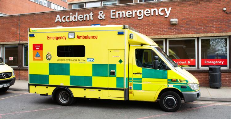 Ambulance parked front of A&E entrance of hospital.