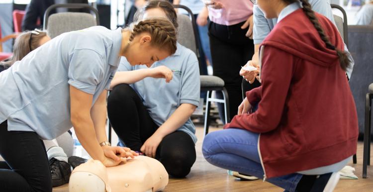 First Aid Training, Girl performing compressions on CPR Dummy