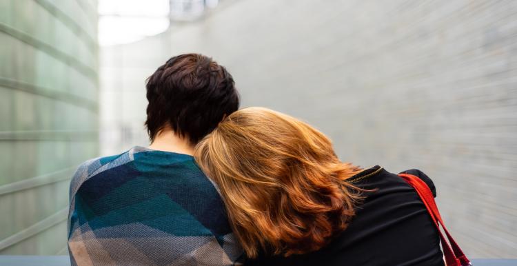 two people sitting close together leaning on each other