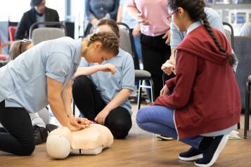 First Aid Training, Girl performing compressions on CPR Dummy